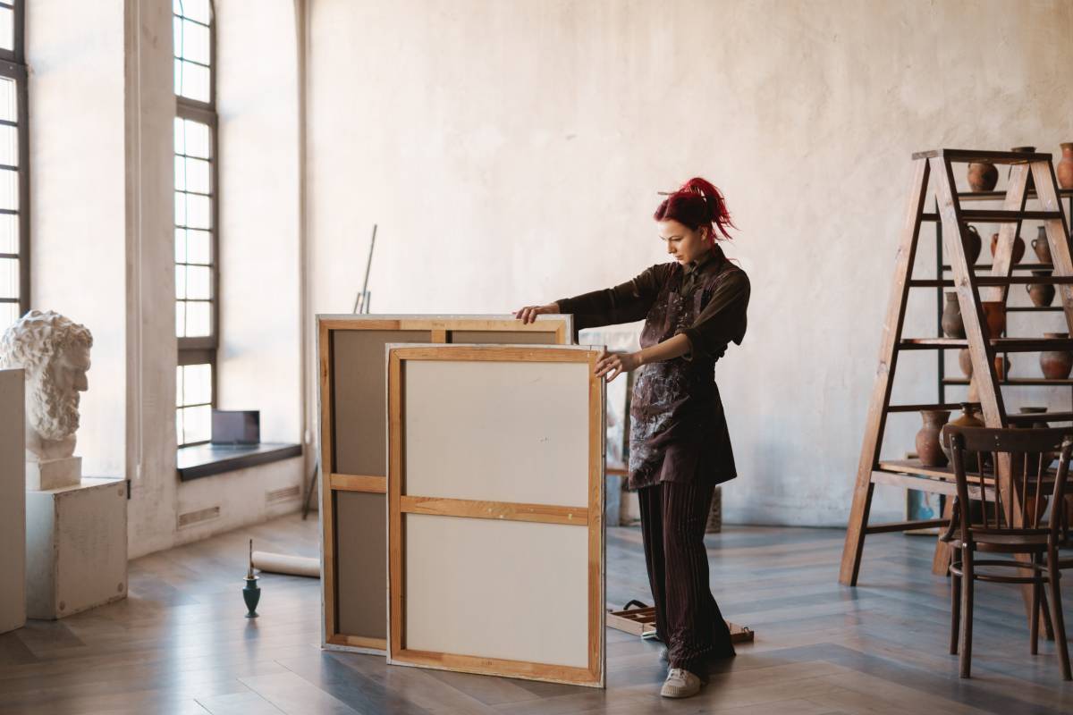 Young white woman painter in an art studio, using laptop computer for ideas