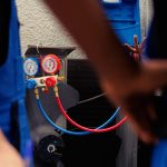 Qualified specialists using pressure measurement device for checking air conditioner refrigerant in need of maintenance. Competent engineering team working with manometers to look at freon levels