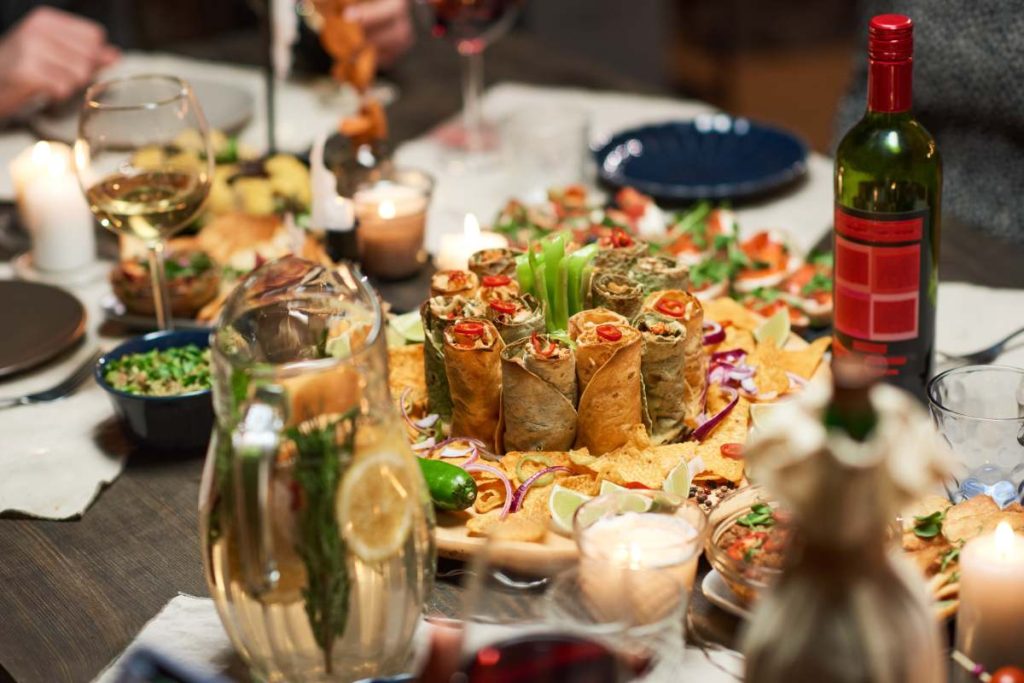Close-up of different delicious appetizers and bottle of red wine on festive dining table