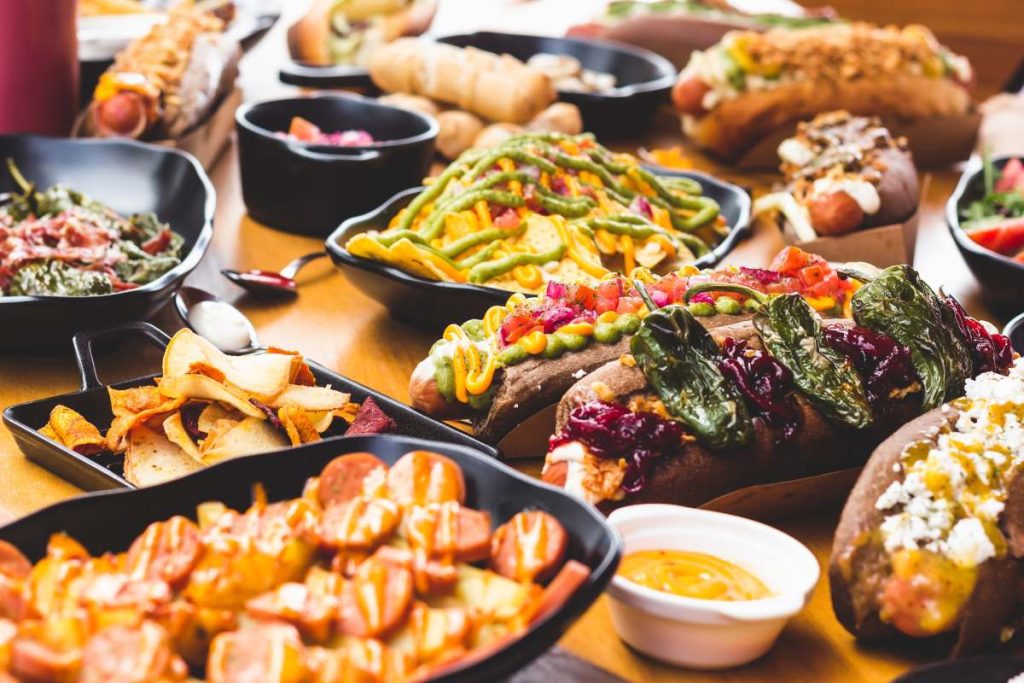 Close-up of plate with nacho chips in dressing served with various snacks on table.