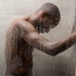 side view of handsome young african american man washing body in shower