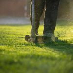 Garden worker with lawn mover. Garden works in spring.